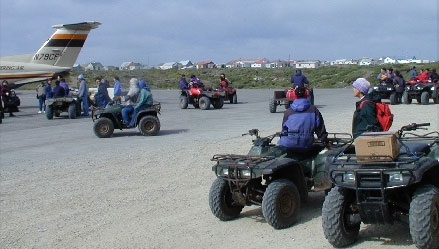 People pick up supplies on the runway from their ATVs